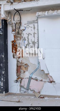 Close-up d'un mur intérieur endommagé avec câblage électrique exposé, isolation et plâtre cassé lors de la démolition et de la rénovation d'un bâtiment résidentiel Banque D'Images