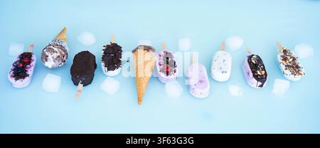 Ronde colorée de bâtonnets glacés maison au yaourt et au lait. Vanille et chocolat décorés de noix et de baies surgelées sur un fond bleu vif. Parfait pour une fête d'anniversaire d'enfants en été. Banque D'Images