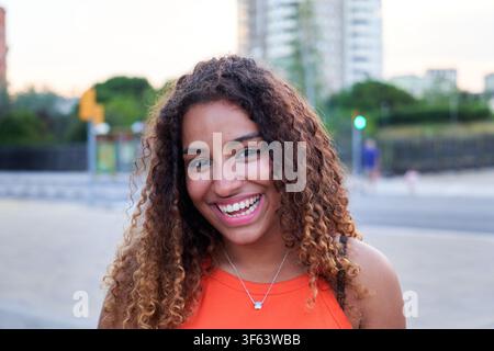 Jeune femme noire souriant à l'extérieur dans un cadre urbain. Banque D'Images