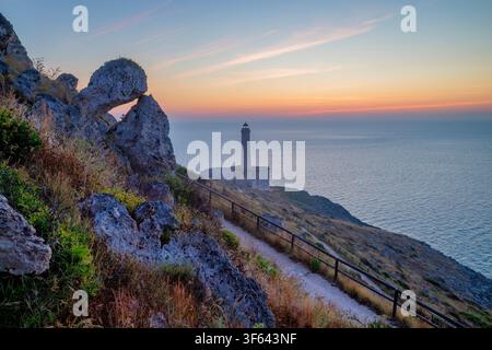 Lever de soleil sur le phare de Punta Palascia avec le sentier côtier serpentant à travers les falaises de calcaire à Capo d'Otranto, Otranto, Lecce, Pouilles, Italie Banque D'Images