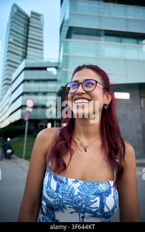 Jeune femme souriante en ville urbaine, profitant d'une journée ensoleillée Banque D'Images