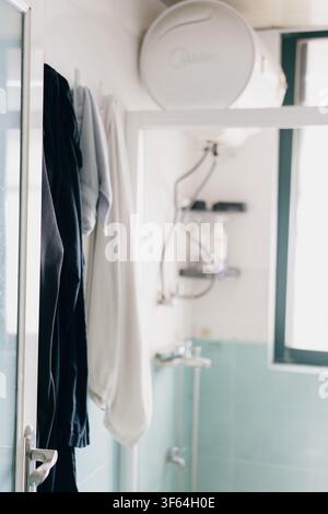 Intérieur de salle de bain moderne dans un appartement résidentiel chinois, avec des robes suspendues, fixées au mur Banque D'Images