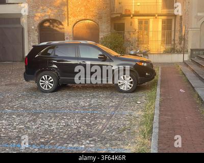 Cremone, Italie, 8 juillet 2026 VUS Kia Sorento noir garé sur une vieille rue pavée de la Piazza Sant'Angelo, Cremone. Lumière chaude se reflétant sur la brique Banque D'Images