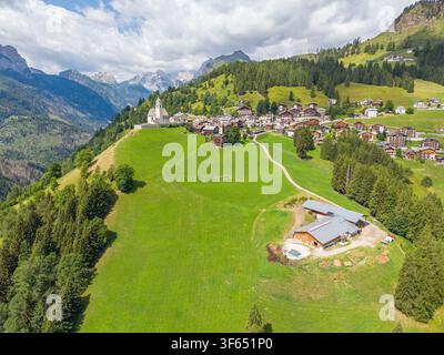 Vue aérienne du village alpin de Colle Santa Lucia avec son église historique, ses maisons traditionnelles et ses prairies verdoyantes dans les Dolomites en Co Banque D'Images