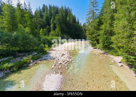 Des forêts conifères luxuriantes bordent les eaux peu profondes et cristallines de la rivière Ammer alors qu'elle serpente à travers le lit rocheux du pittoresque Ammer Go Banque D'Images