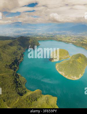 Vue aérienne de la Laguna de Cuicocha avec son lac de cratère volcanique turquoise, ses îles verdoyantes et les montagnes andines environnantes sous un ciel nuageux en Banque D'Images
