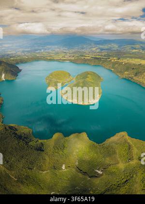 Vue aérienne des eaux turquoise du lac de cratère Laguna de Cuicocha avec ses îles centrales entourées de pentes volcaniques vertes et luxuriantes à Cotacachi Banque D'Images