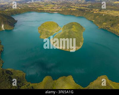 Vue aérienne de la Laguna de Cuicocha, un lac de cratère volcanique avec deux îles centrales entourées de pentes vertes luxuriantes et d'un terrain accidenté à Cotacachi, Im Banque D'Images