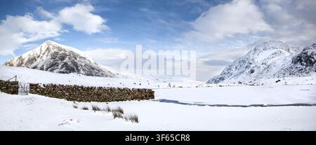 Vue panoramique hivernale de la vallée d'Ogwen enneigée, mettant en scène une rive gelée du Llyn Idwal, un mur de pierre, Pen yr Ole Wen et Tryfan au Pays de Galles. Banque D'Images