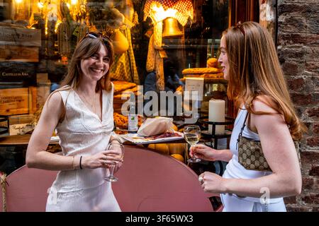 Deux touristes britanniques profitent d'un verre de vin et d'une assiette de spécialités locales devant une épicerie fine, à Sienne, en Toscane, Italie. Banque D'Images