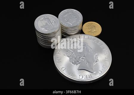 Pièce d'argent en lingots avec des piles de pièces en argent et une pièce en or sur fond noir. Concept de métaux précieux, investissement, richesse, épargne Banque D'Images