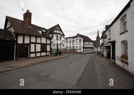 Bâtiments historiques en bois noir et blanc de style Tudor le long de Broad Street avec vue sur le clocher de l'église à Weobley, Herefordshire. Banque D'Images