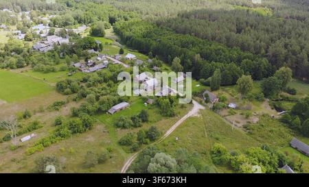 Vue aérienne d'un petit village bordant une forêt luxuriante en été Banque D'Images
