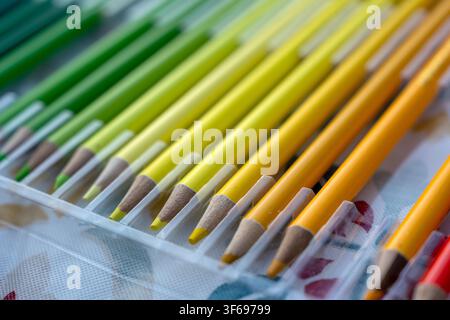 Une photographie en gros plan, lumineuse et vibrante, mettant l'accent sur des crayons de couleur aux tons chauds, y compris des jaunes, des oranges et des rouges vifs, disposés soigneusement dans un ordre clair Banque D'Images