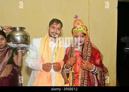 Mariee bengali indienne en tenue de mariée rouge avec couronne traditionnelle et marié en sherwani blanc avec écharpe jaune lors d'un rituel de mariage en Inde. Une femme Banque D'Images