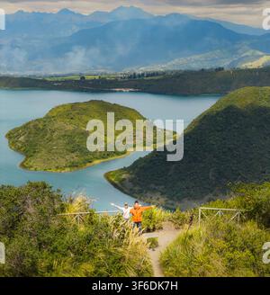 Vue aérienne de la Laguna de Cuicocha avec ses îles, entourée de collines et montagnes luxuriantes, avec deux personnes debout sur un point de vue à Cotacachi Banque D'Images