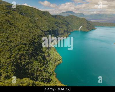 Vue aérienne de la Laguna de Cuicocha présentant des eaux turquoise d'un lac de cratère volcanique entourées de montagnes andines luxuriantes et d'un ciel bleu éclatant à C Banque D'Images