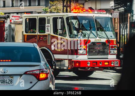SAN FRANCISCO, ÉTATS-UNIS - SEPTEMBRE 2024 : Camion-pompière de la San Francisco Fire Department avec gyrophares d'urgence roulant dans une rue de la ville en Californie Banque D'Images