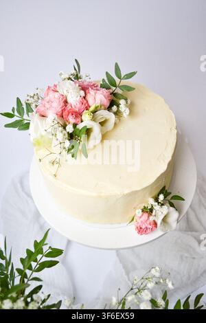 Gâteau blanc givré élégant décoré d'un bouquet de fleurs fraîches roses et blanches Banque D'Images