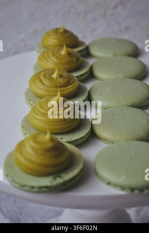 Pile de macarons aux pistaches verts avec crème au beurre et pistaches concassées en gros plan Banque D'Images