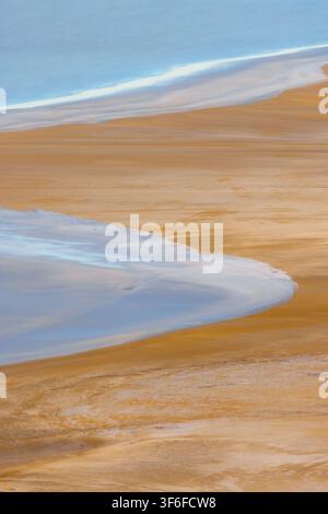 Vue aérienne des salines de Karynzharyk avec de vastes textures de sable doré et des bassins d'eau bleue réfléchissants dans le district de Karakiya, région de Mangystau, Kazakhstan Banque D'Images