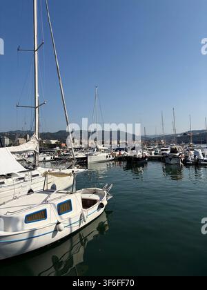 Des voiliers et des yachts blancs amarrés dans une marina méditerranéenne par une journée ensoleillée avec une eau calme et un ciel bleu clair. Banque D'Images