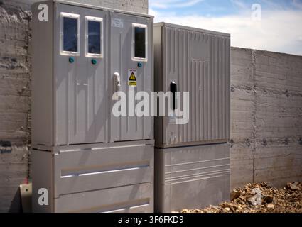 Boîte de distribution électrique extérieure grise et armoire de comptage installées contre un mur en béton. Banque D'Images