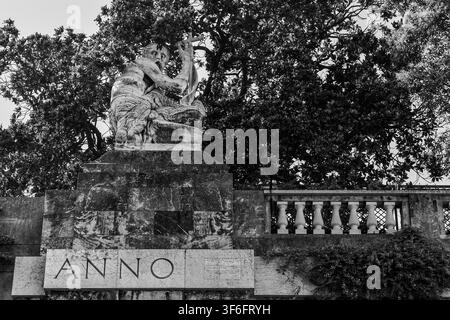 Photo noir et blanc d'une statue en pierre représentant un ermite agenouillé (Saint Jean-Baptiste ?) tenant une croix sur la Piazza del Portello, Gênes, Italie Banque D'Images