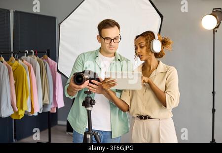 Équipe de photographes examinant les prises de vue sur une tablette à côté de l'appareil photo dans un studio moderne Banque D'Images