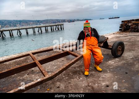 Un pêcheur chilien se repose sur un chariot à bateaux à Caleta Portales, un port de pêche artisanal à Valparaíso, au Chili. Banque D'Images