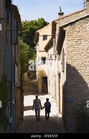 Couple se tenant la main en marchant dans une rue pavée tranquille à Gordes, Provence, France. Banque D'Images