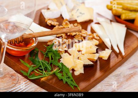 Différents types de fromage servis sur bois avec du miel, des tranches de noix Banque D'Images