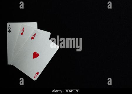 Trois cartes à jouer, les as de trèfle, de carreau et de cœur sur un fond en tissu sombre moucheté, suggérant le succès, l’habileté et la chance. Banque D'Images