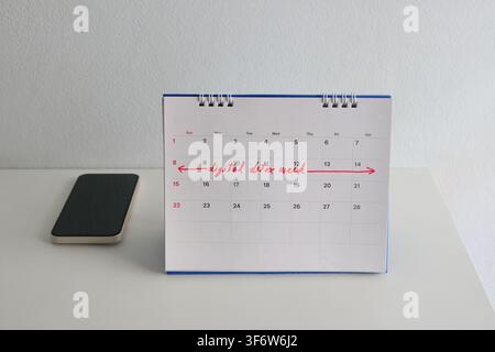 Focus sélectif sur la phrase écrite à la main "semaine de détox numérique" en encre rouge sur le calendrier de bureau, un smartphone éteint est placé à côté. La mise en place est sur Banque D'Images