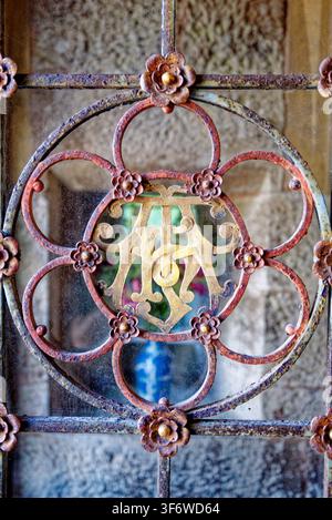 Grille de porte en fer forgé rouillé antique arborant un médaillon monogrammé doré détaillé, photographiée à Knightshayes Court, Tiverton, Devon, Angleterre, le Banque D'Images