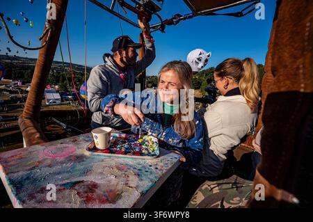 Artiste Emily Powell photographiée dans un panier de montgolfière, où elle peint en direct depuis l'intérieur d'un panier de montgolfière lors de la 48e Bristol International Balloon Fiesta, un festival annuel gratuit de montgolfières, qui est le plus grand événement de ce genre en Europe. Date de la photo : vendredi 7 août 2026. Banque D'Images