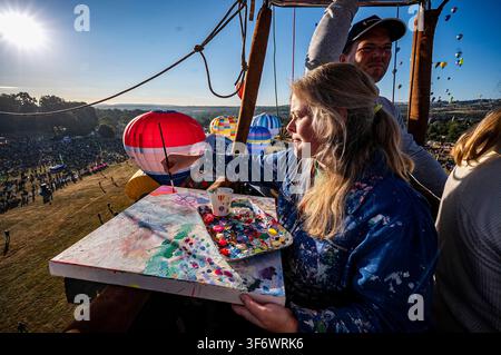 Artiste Emily Powell photographiée dans un panier de montgolfière, où elle peint en direct depuis l'intérieur d'un panier de montgolfière lors de la 48e Bristol International Balloon Fiesta, un festival annuel gratuit de montgolfières, qui est le plus grand événement de ce genre en Europe. Date de la photo : vendredi 7 août 2026. Banque D'Images