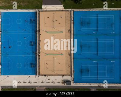 Vue aérienne de dessus d'un complexe sportif en plein air avec des terrains de basket-ball, de beach-volley et de tennis, une installation multisports urbaine et un concept de loisirs. Banque D'Images