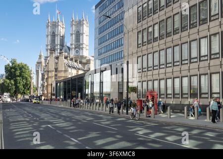 Les piétons explorent Victoria Street à Londres, passant devant une cabine téléphonique rouge emblématique avec vue sur l'abbaye de Westminster et Big Ben. Banque D'Images