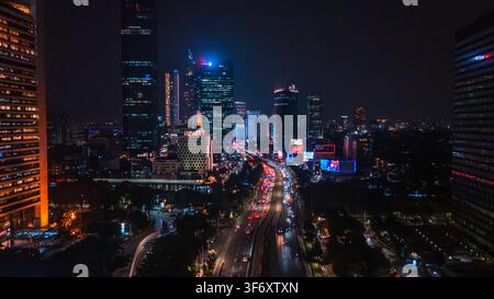 Vue aérienne de la skyline illuminée de Jakarta la nuit avec des gratte-ciel et la circulation s'écoulant le long de l'autoroute à Jakarta, Indonésie Banque D'Images