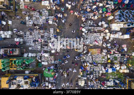 Vue aérienne d'un marché aux poissons animé avec des vendeurs et des acheteurs naviguant entre des caisses de poisson frais, des conteneurs colorés et des camions de transport à Chatto Banque D'Images