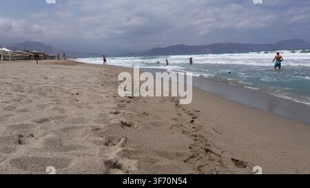 Vue large de la plage de sable d'Episkopi et du littoral avec des vagues se brisant sous un ciel nuageux à Rethymno, Crète, Grèce. Banque D'Images