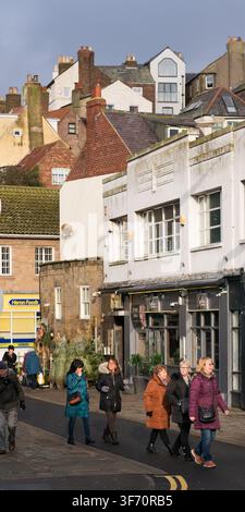 Les touristes passent devant des sapins de Noël et Heron Foods sur Flowergate à Whitby, profitant d'une journée dans la ville historique du North Yorkshire. Banque D'Images