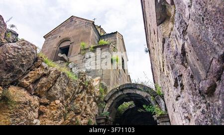 Arches d'un ancien pont de pierre sous des falaises abruptes. Des ruines d'église érodées se dressent sur un terrain rocheux Banque D'Images