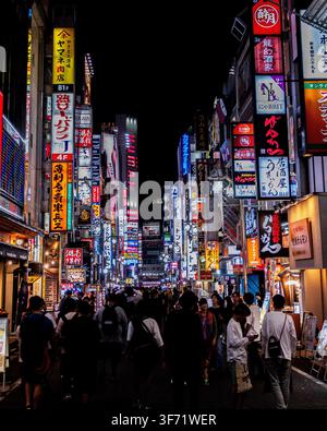 Tokyo, Japon – juin 2025 : des foules de piétons déambulent dans une rue Kabukicho illuminée aux néons à Shinjuku, bordée de bars, restaurants et panneaux publicitaires lumineux Banque D'Images
