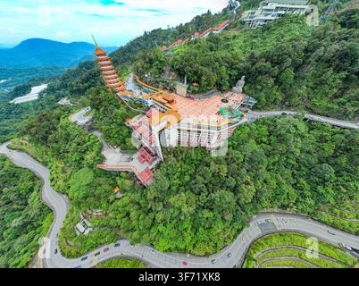 Vue aérienne du temple des grottes Chin Swee avec sa pagode emblématique et sa grande statue de Bouddha au milieu des forêts montagneuses luxuriantes et des routes sinueuses de Genting Hig Banque D'Images