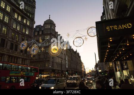 Le trafic nocturne défile devant le Savoy Hotel historique et le Theatre on the Strand à Londres, ornés des lumières festives de Noël de Northbank. Banque D'Images