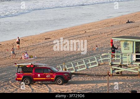 Une tour de sauvetage et un camion de sauvetage du comté de Los Angeles se trouvent sur la plage de sable tandis que des visiteurs marchent le long du rivage près de l'océan Pacifique. Banque D'Images