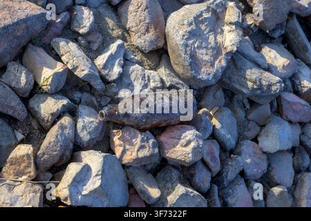 Bouteille de bière en verre abandonnée parmi les rochers côtiers représentant la pollution par les déchets et l'impact humain sur l'environnement naturel Banque D'Images