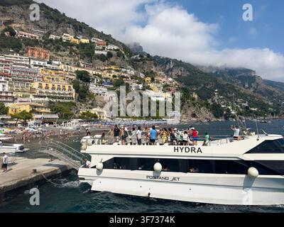 Ferry à passagers Hydra de Positano Jet dans le port animé de Positano, avec des touristes, une plage et des bâtiments sur les falaises de la côte amalfitaine en Italie. Banque D'Images